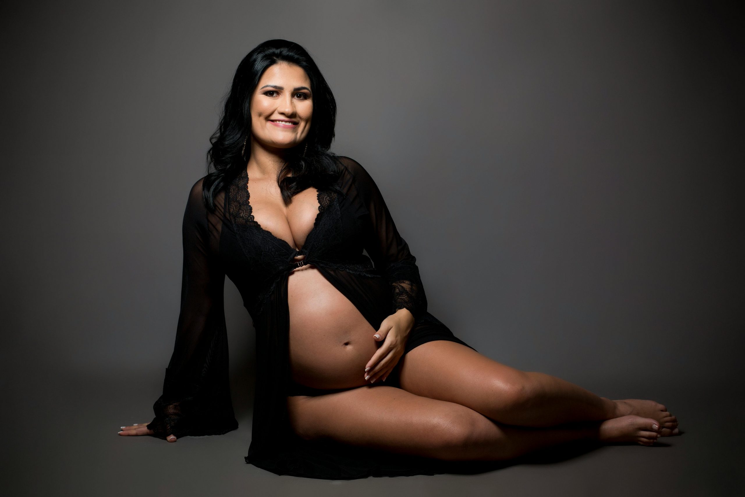 pregnant woman sitting with her legs tucked to one side while posing